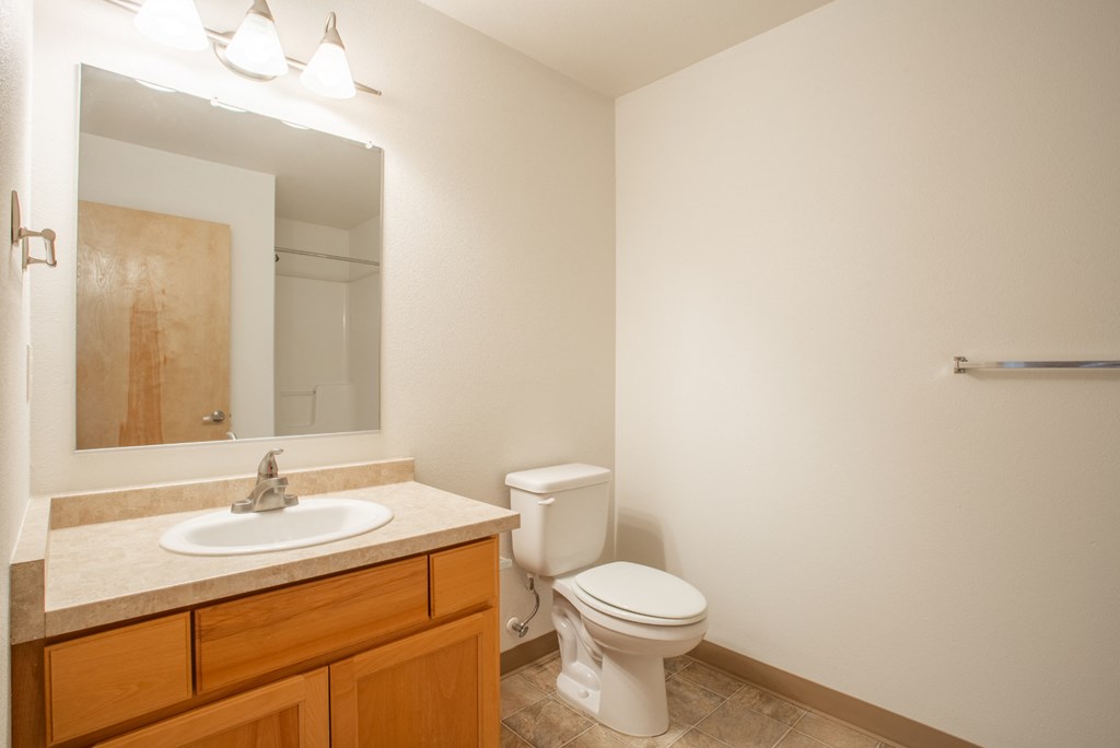 an empty bathroom with a toilet sink and mirror