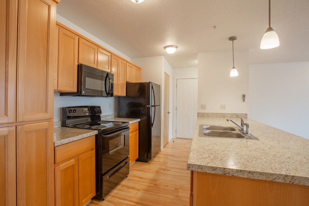 a kitchen with black appliances and granite counter tops and wooden cabinets