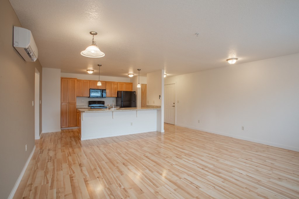 an empty living room and kitchen with wood flooring