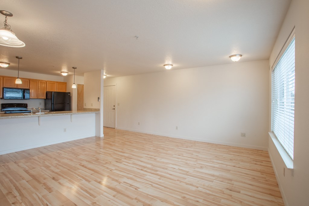 an empty living room and kitchen with wood flooring