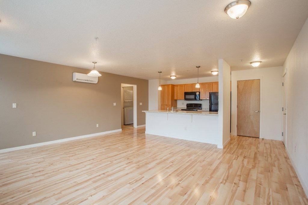 an empty living room and kitchen with wood flooring