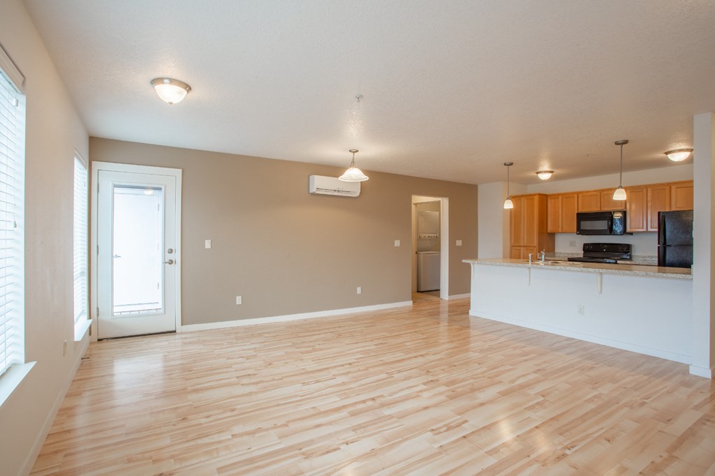an empty living room and kitchen with wood flooring