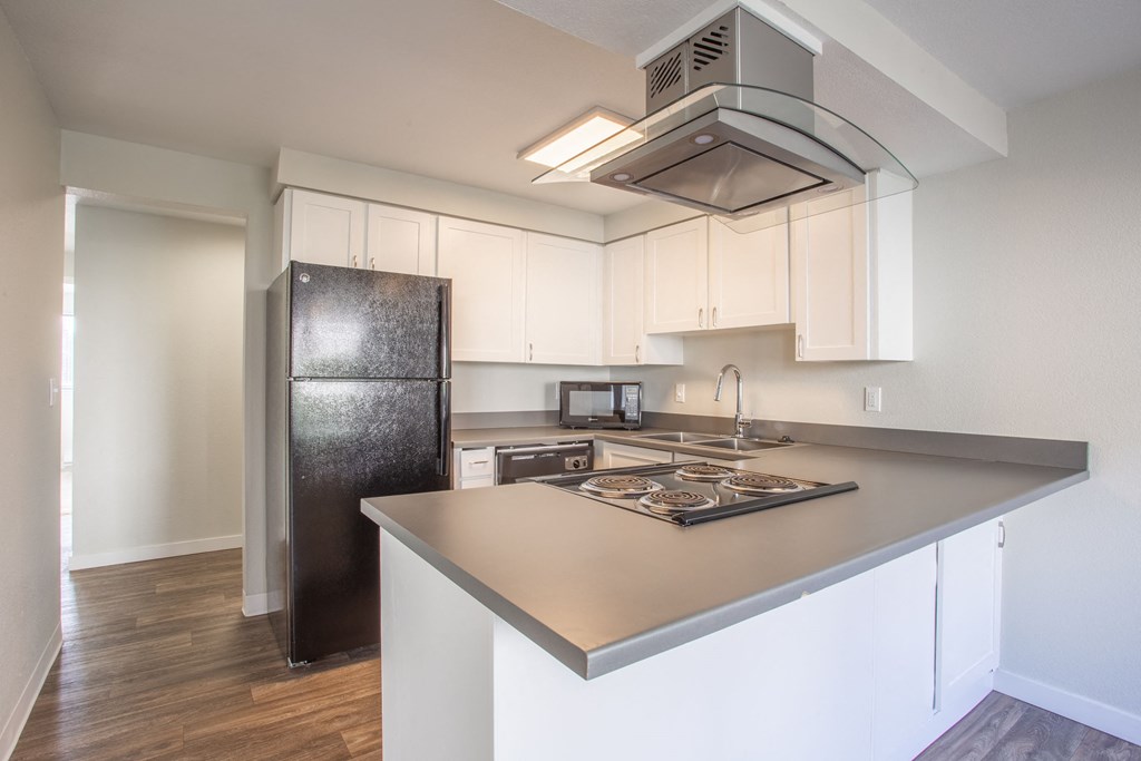 a kitchen with white cabinets and a black refrigerator