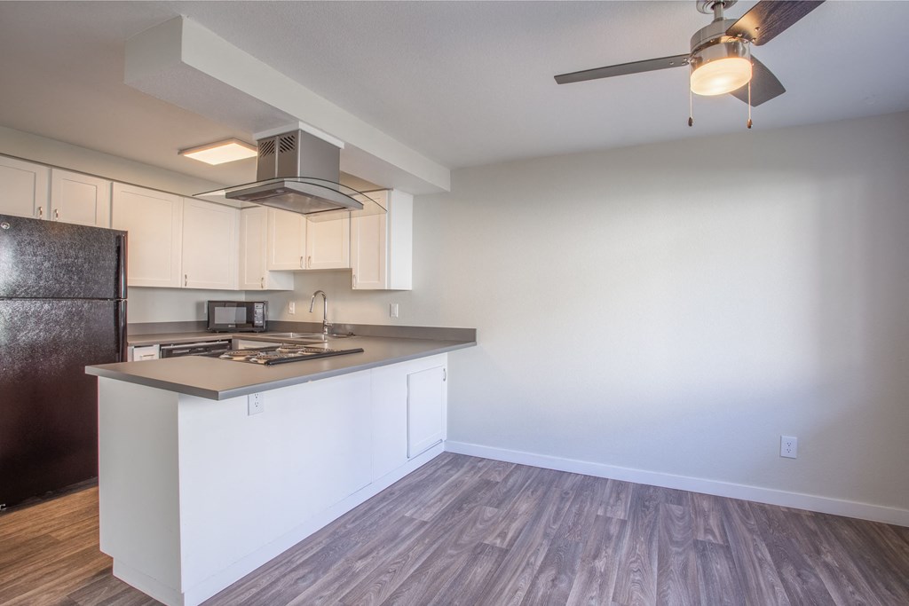 an empty kitchen with white cabinets and a counter top and a refrigerator
