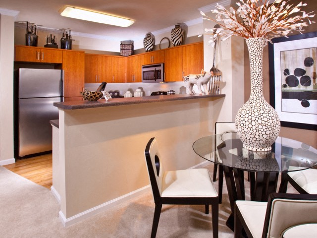 a living room with a glass table and a kitchen