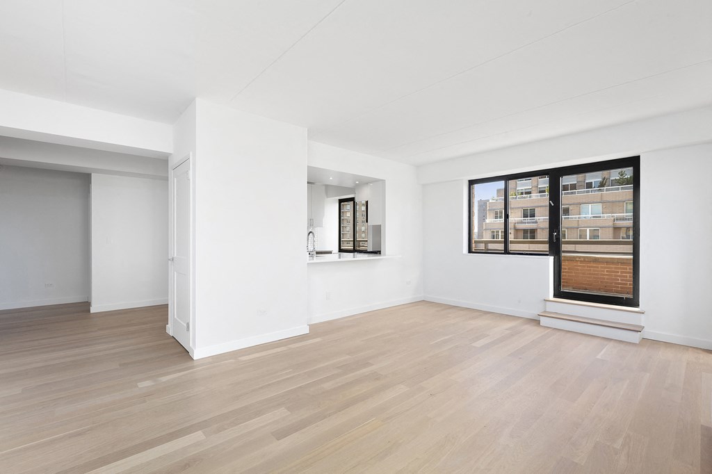 a living room with white walls and a large window and wooden floors