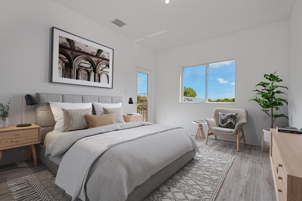 Modern bedroom with gray upholstered bed, balcony access, and sitting area.