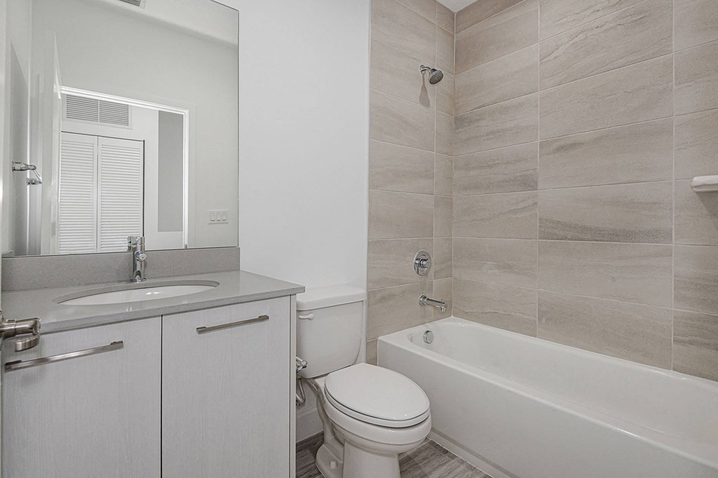 Pearl at Pompano Beach Townhomes in Pompano Beach, FL Modern bathroom with vanity, toilet, and tiled bathtub.