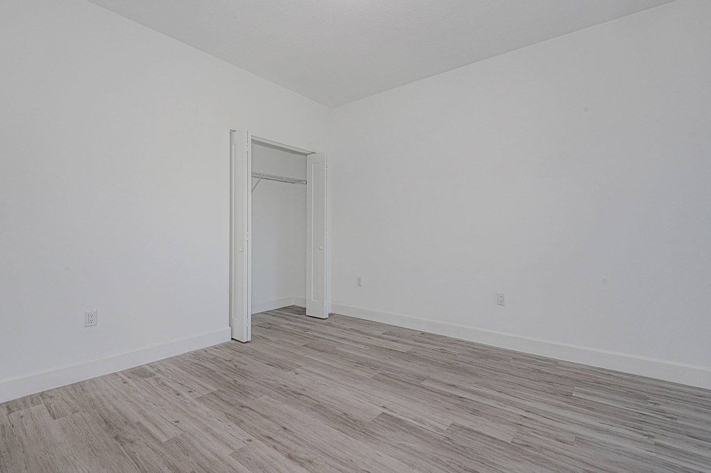 Pearl at Pompano Beach Townhomes in Pompano Beach, FL Empty white bedroom with wood-look flooring and closet.