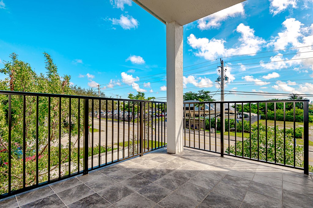 Pearl at Pompano Beach Townhomes in Pompano Beach, FL Balcony with black railings overlooking a street and blue sky.