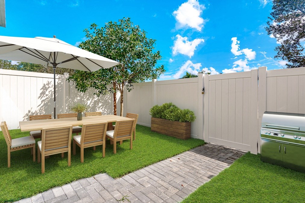 Outdoor dining set with umbrella, grill, and white fence in backyard.