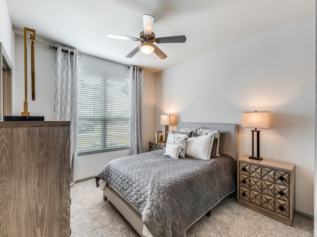 A bedroom with a bed, nightstand, and a ceiling fan.