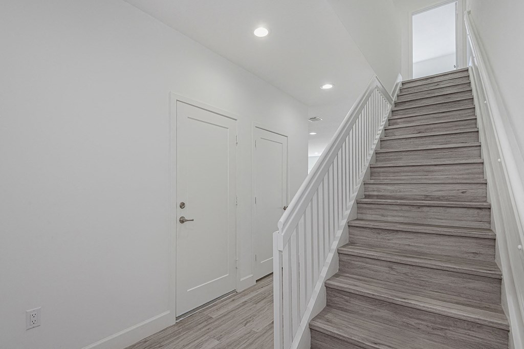 Pearl at Pompano Beach Townhomes in Pompano Beach, FL Modern white hallway with wood-look tile flooring and staircase.