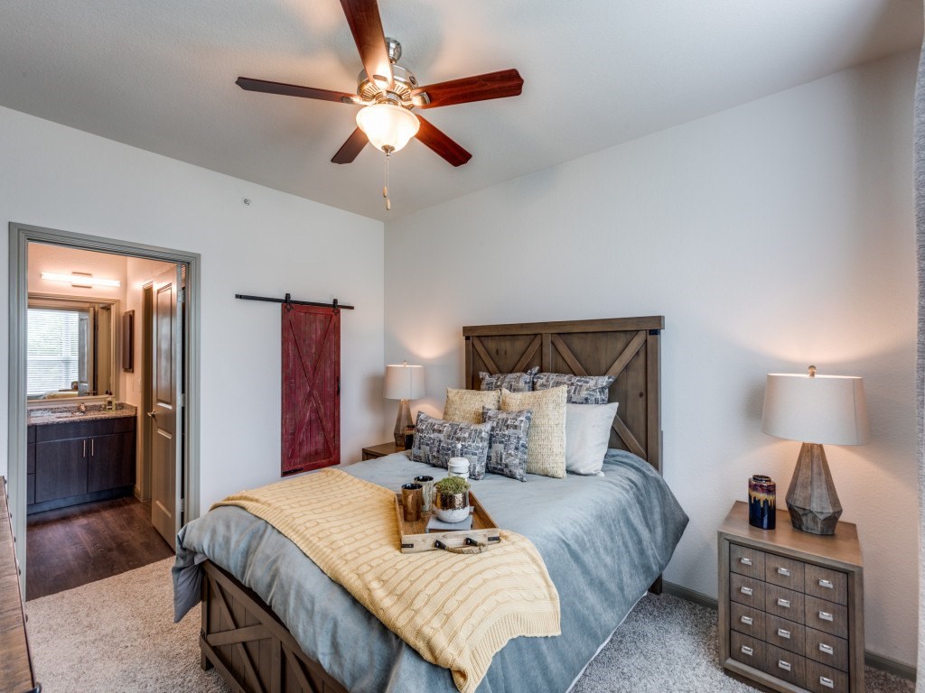 A bedroom with a bed, nightstand, and a ceiling fan.