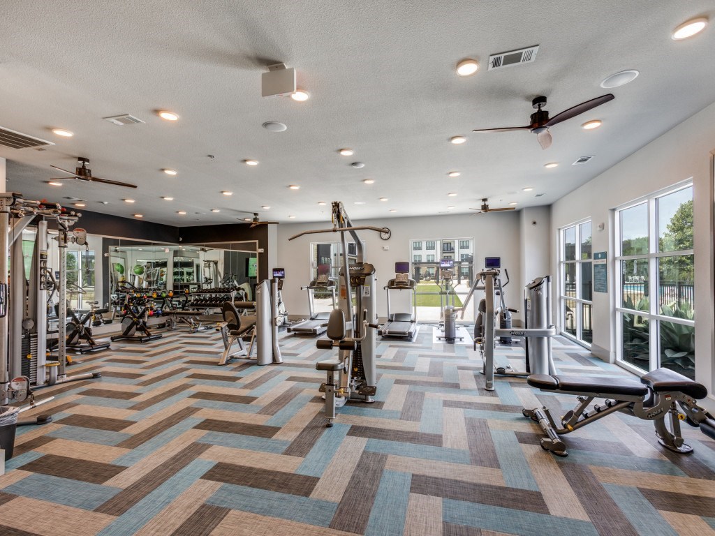 A gym with a variety of equipment including treadmills, weights, and exercise machines.