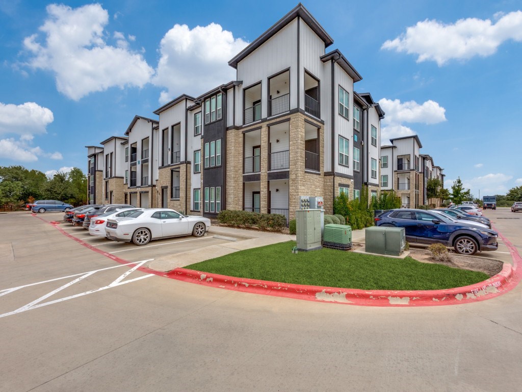 A white car is parked in a parking lot in front of a building.