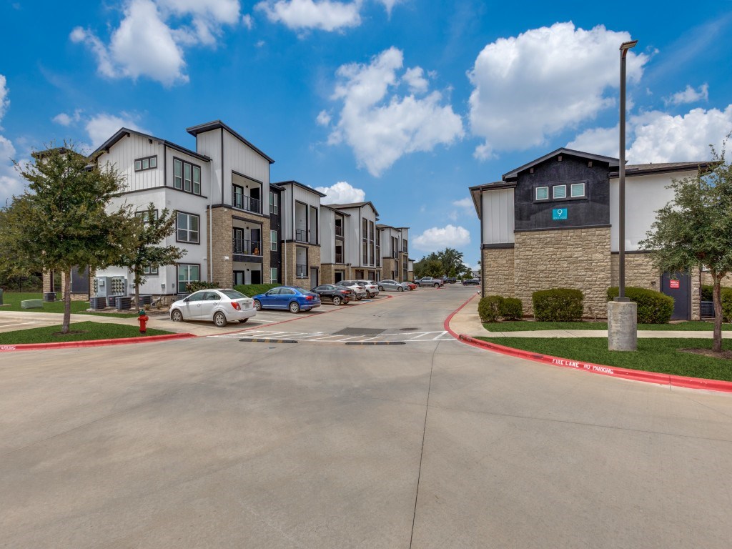 A parking lot in front of a building with a blue car parked.