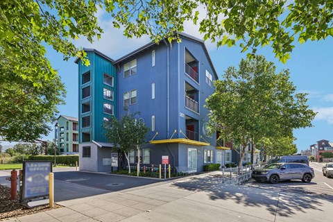 A blue and green building with a parking lot in front.