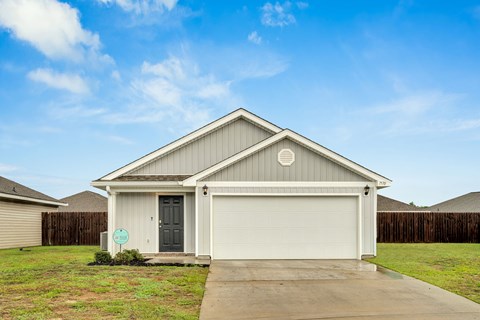 A house with a grey garage door and a green sign in front.