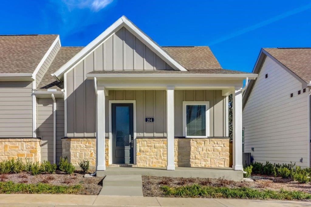 Two Bedroom Single Family Homes for Rent in Hurst TX - Mission Town Square - Front View of Rental Home with Steps, a Covered Porch, a Front Door, a Window, and Light Grey, White, and Brick Detailing