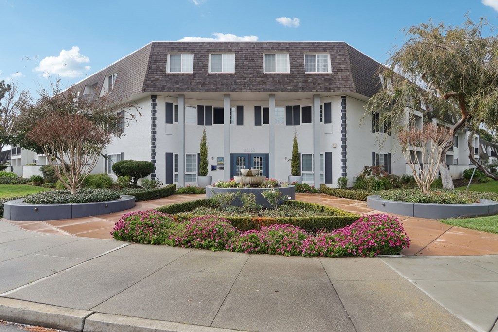 Fremont, CA Apartments For Rent - Brookvale Chateau - Front Of Apartment Building Entrance With Lush Greenery And Florals