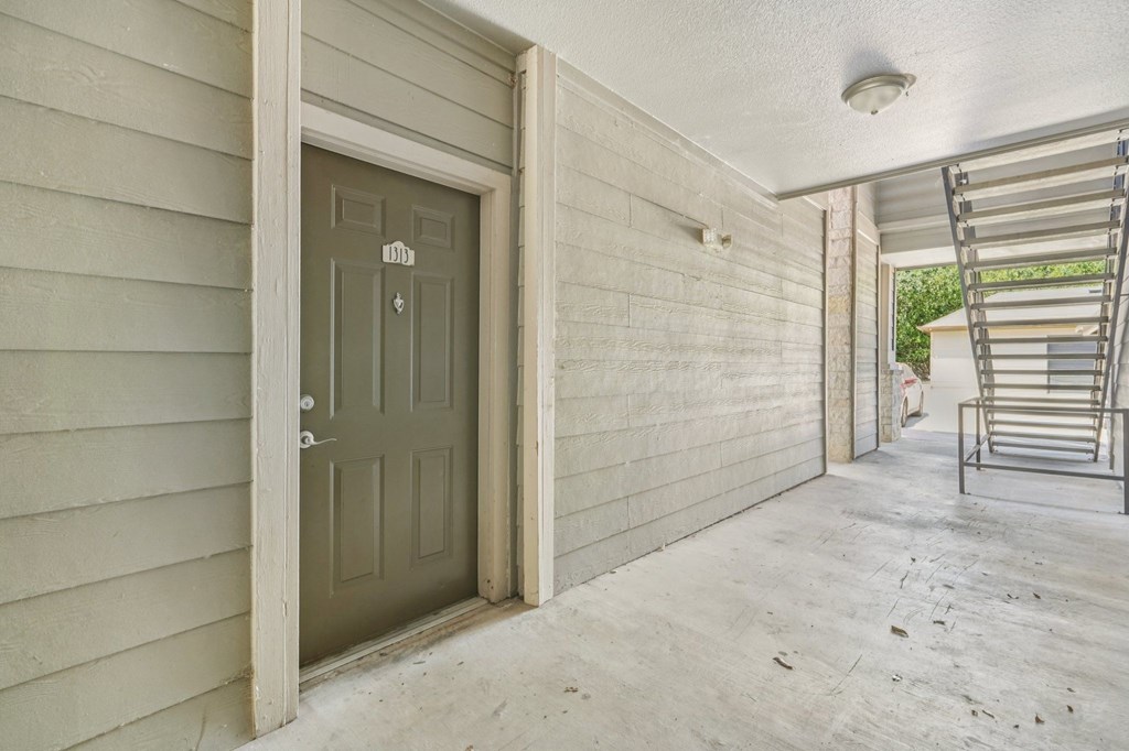 A grey door is on the left side of a room with a white ceiling.