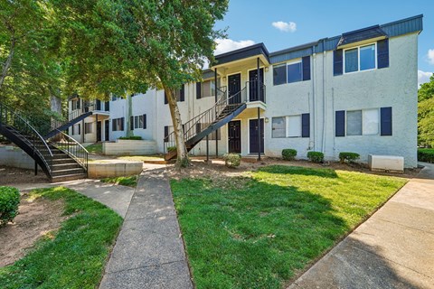 A concrete pathway leads to a building with a tree in front.