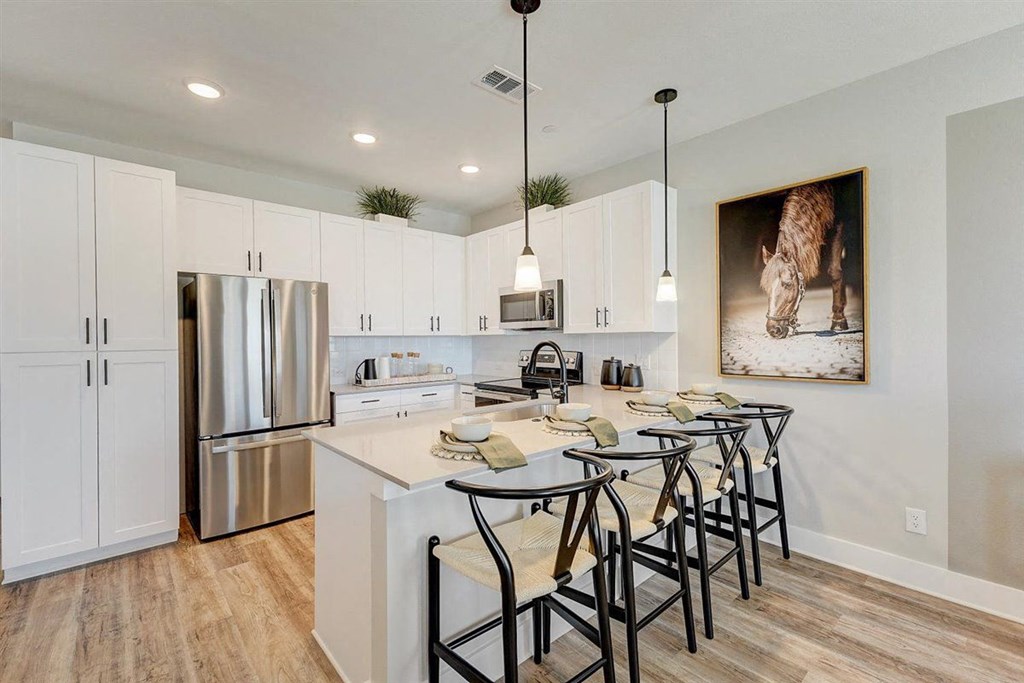 a kitchen with white cabinets and a stainless steel refrigerator