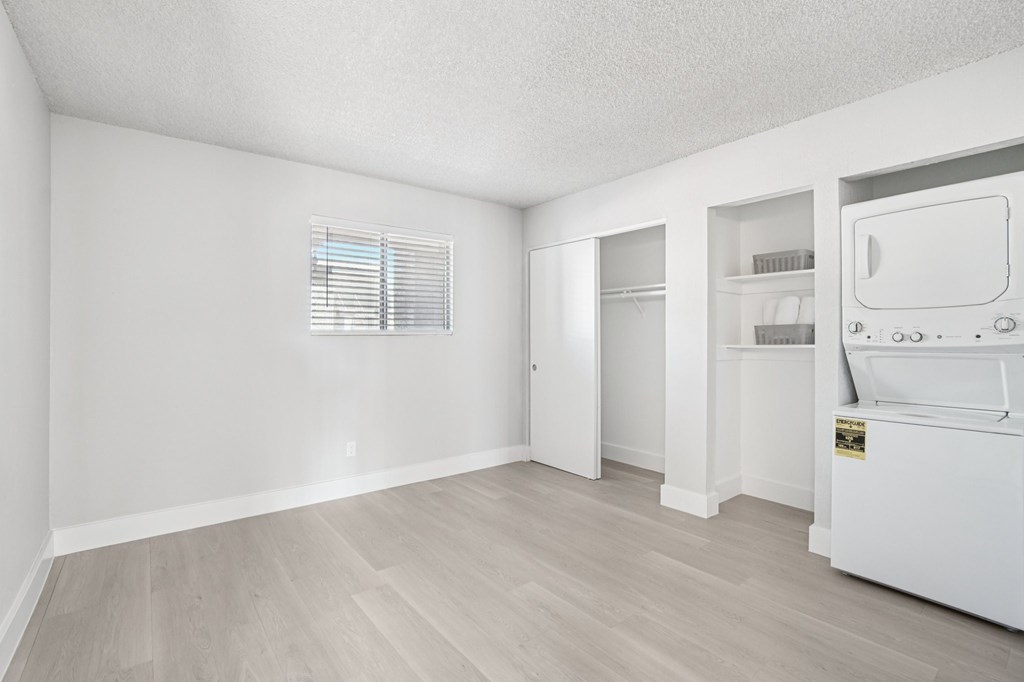 A white fridge in a room with white walls and wooden flooring.