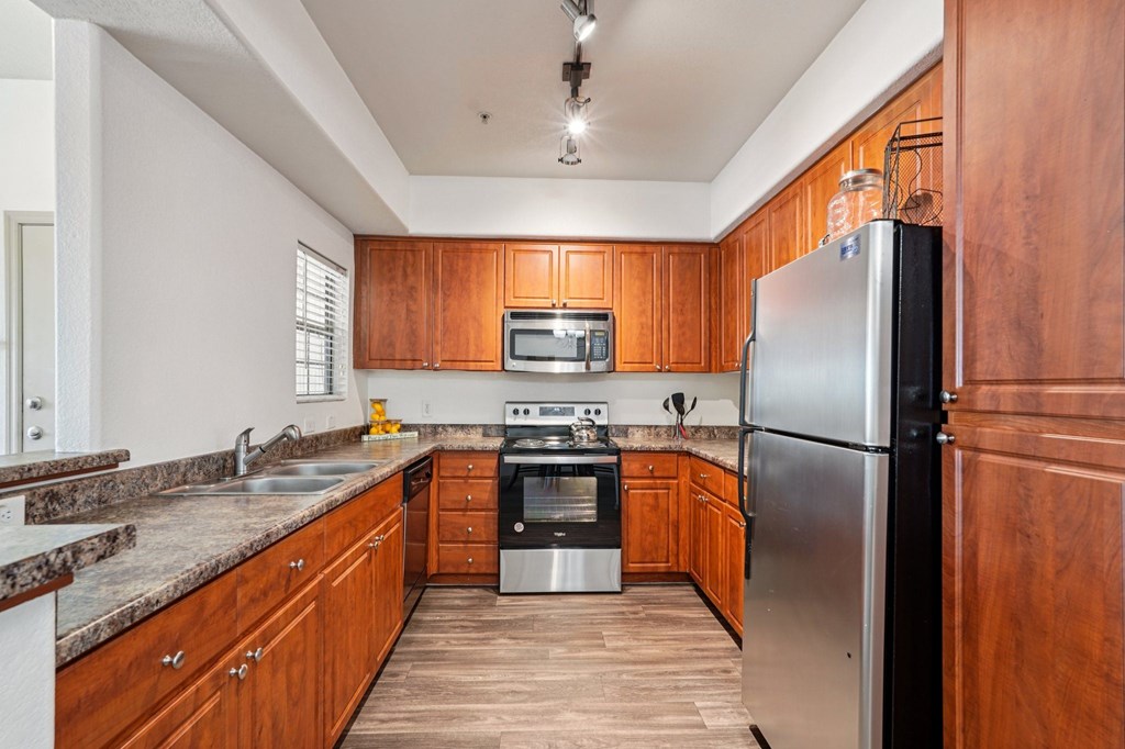 A kitchen with wooden cabinets and a stainless steel refrigerator.