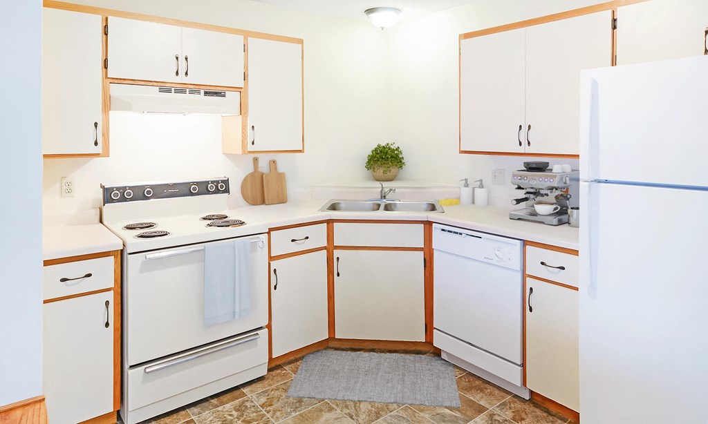 A kitchen with white appliances and wooden cabinets.