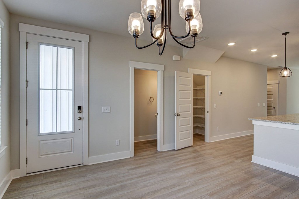 an empty living room with a door to a closet and a chandelier