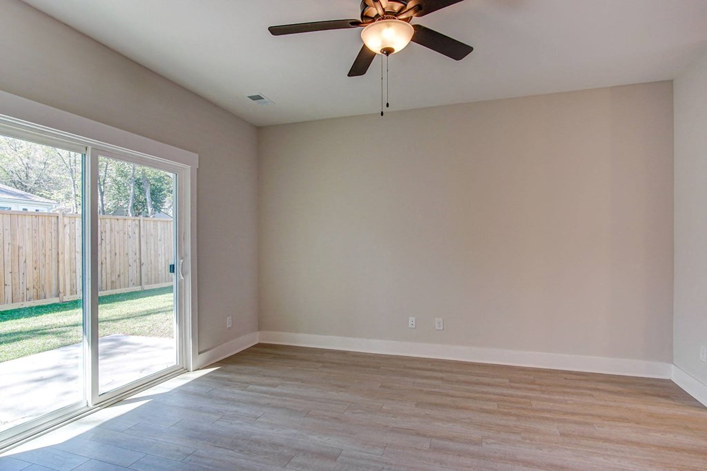 an empty living room with a sliding glass door and a ceiling fan