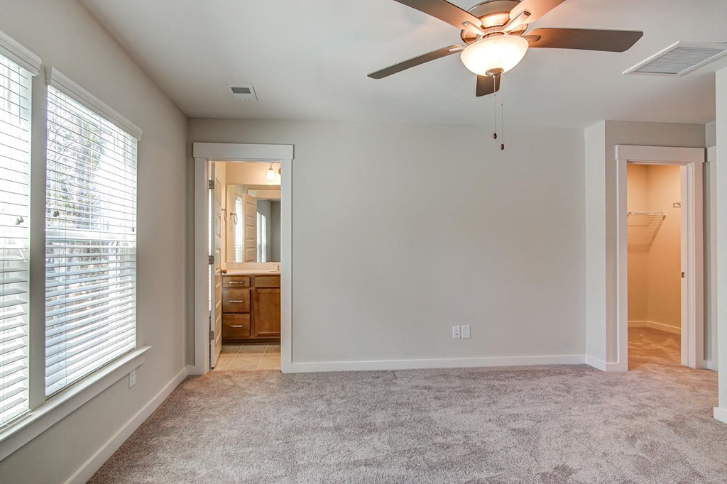 Dog-Friendly Homes for Rent in North Charleston, SC - Sumner Village - Bedroom with Plush Carpet Flooring, Ceiling Fan, Spacious Closet, Attached Bathroom, and Large Windows.