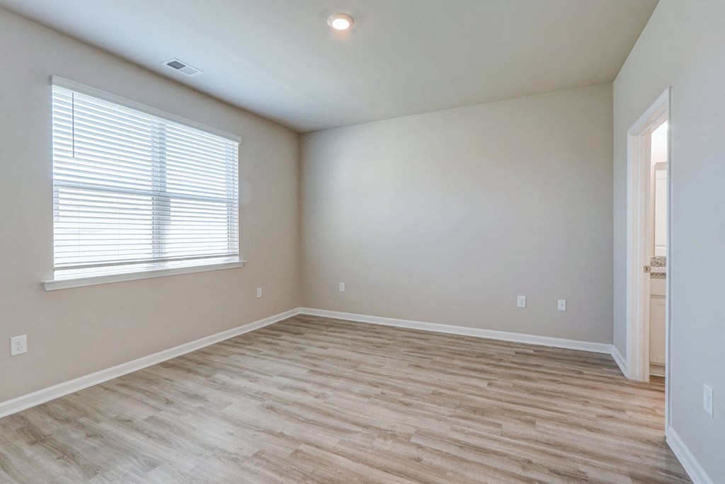an empty living room with wood flooring and a window