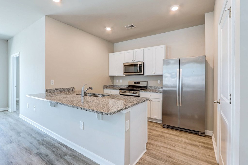 a kitchen with a granite counter top and a stainless steel refrigerator