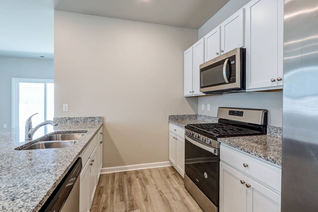 Three-Bedroom Homes for Rent in Myrtle Beach, SC - The Palmer at Carolina Forest - Kitchen with Granite Countertops, Stainless Steel Appliances, White Cabinets, and Vinyl Plank Flooring