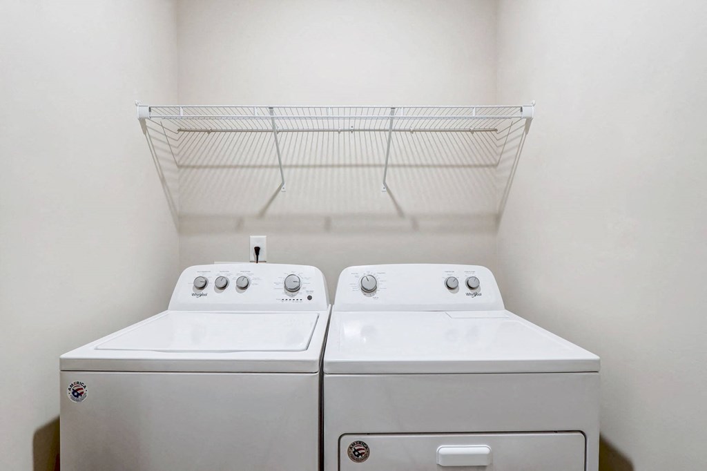 a washer and dryer in a laundry room with a shelf on the wall