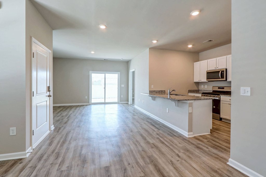 an empty living room with a kitchen with a counter top
