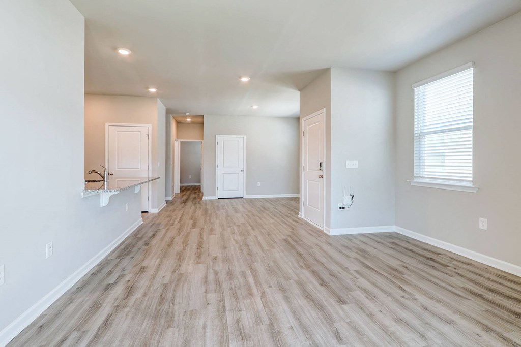 a spacious living room with a hard wood floor and white walls