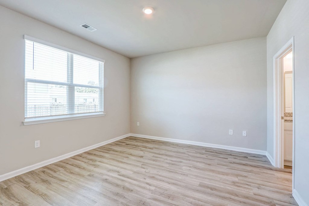 an empty living room with wood flooring and a window