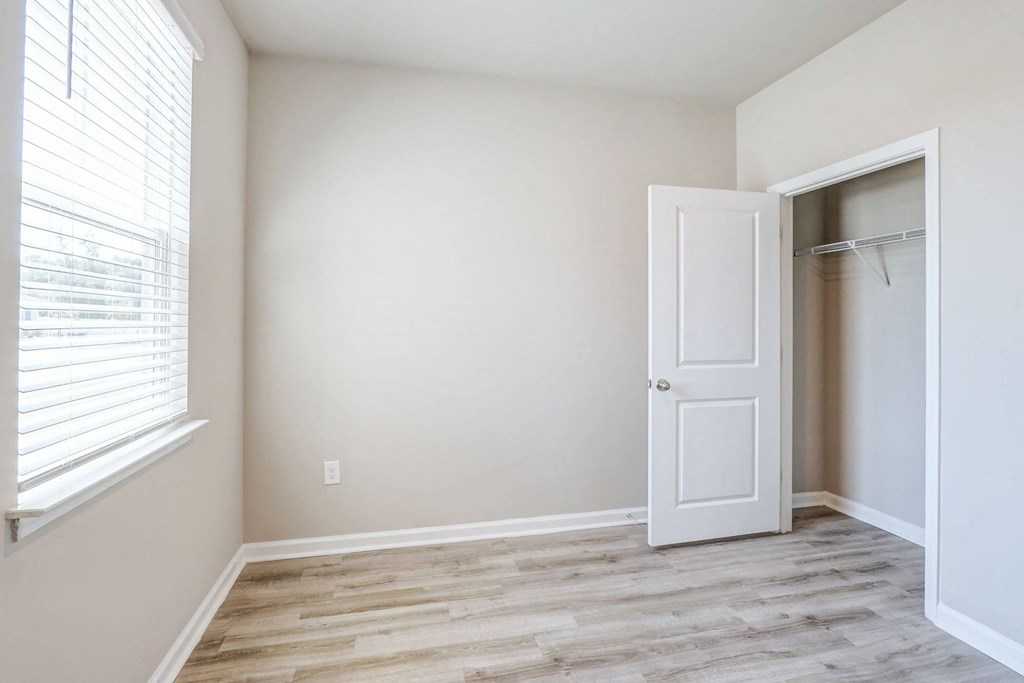 an empty bedroom with a closet and a window