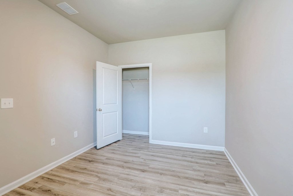 a bedroom with white walls and a closet with a door