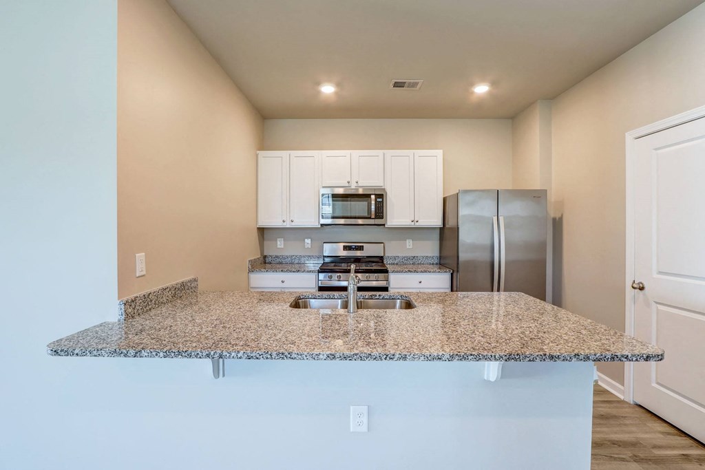 a kitchen with a granite counter top and a stainless steel refrigerator