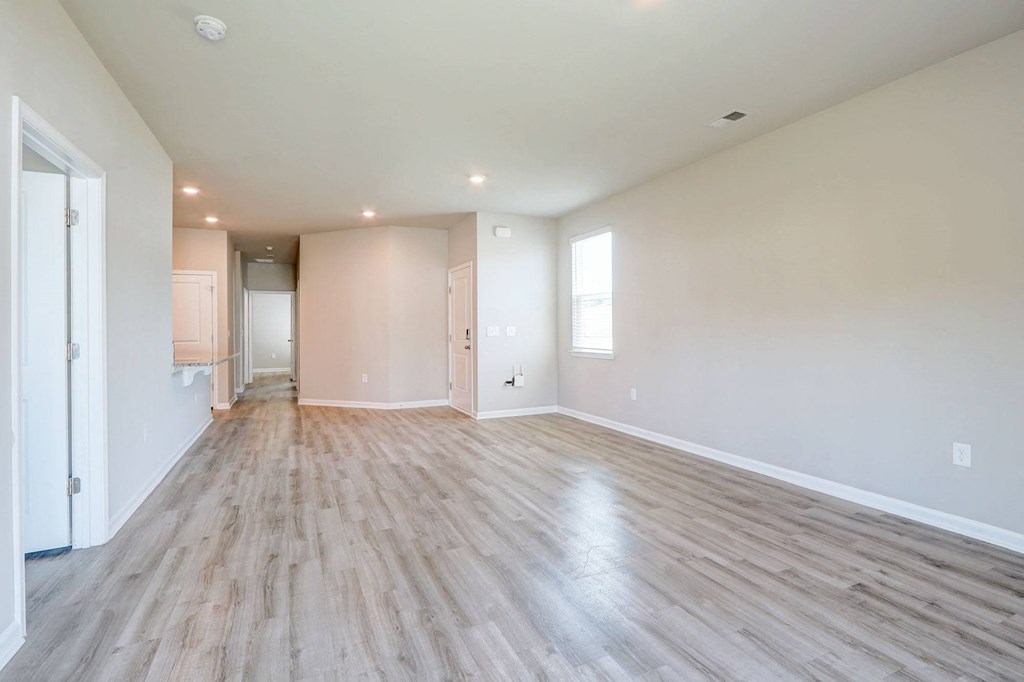 the living room and dining room of an empty house with wood flooring