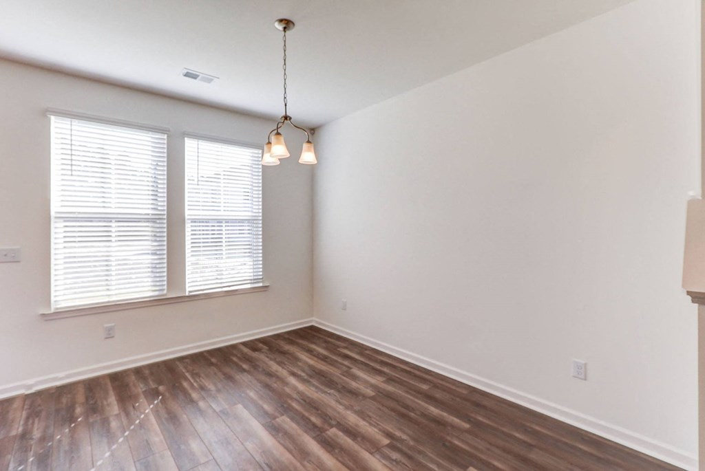 an empty living room with wood flooring and a window