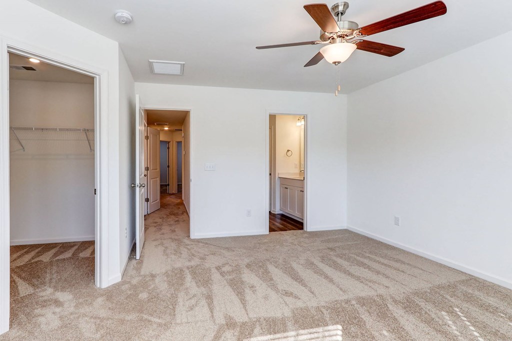 an empty living room with a ceiling fan and a closet