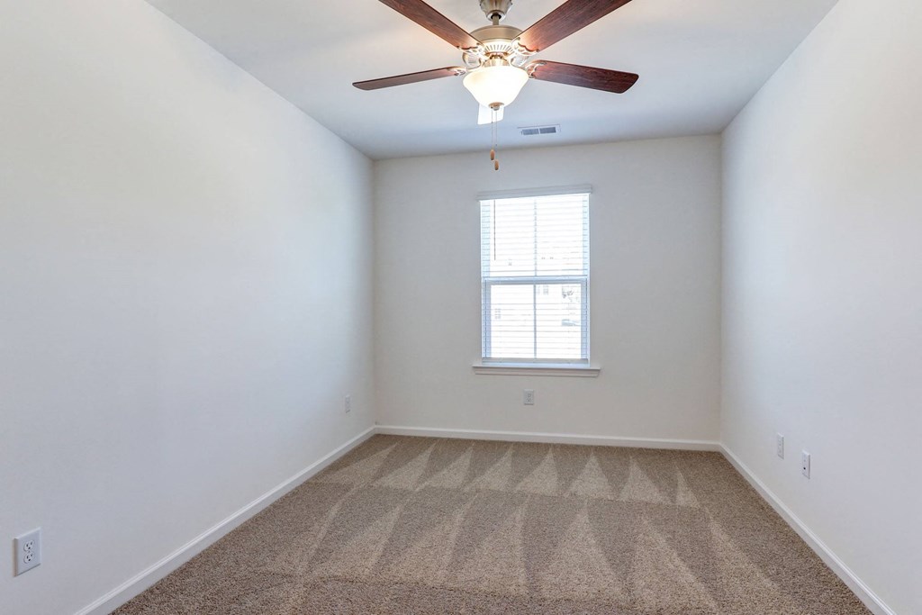an empty room with a ceiling fan and a window
