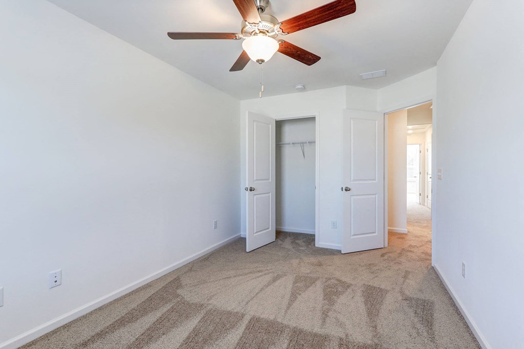 Three-Bedroom Townhomes in North Charleston, SC - Highland Townhomes - Carpeted Bedroom with White Walls, Ceiling Fan, and Large Closet.