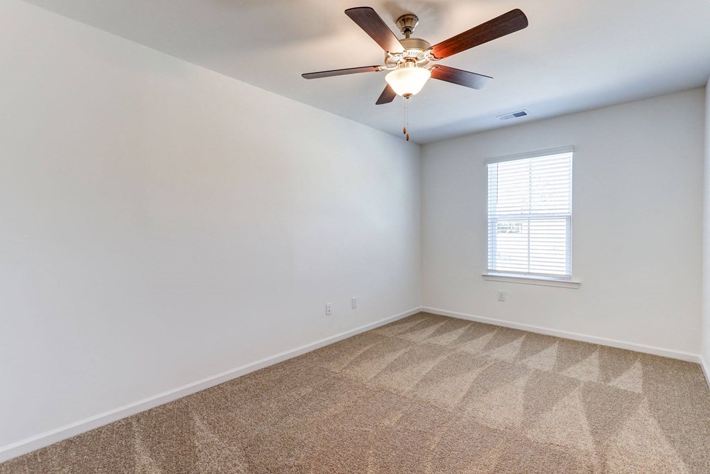 an empty room with a ceiling fan and a window